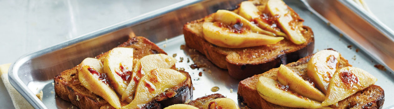 four cinnamon toast on a baking sheet topped with sliced pears