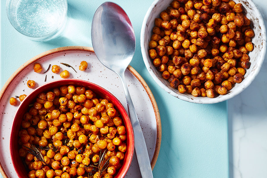 Two bowls of roasted crispy chickpeas on a blue board on marble background