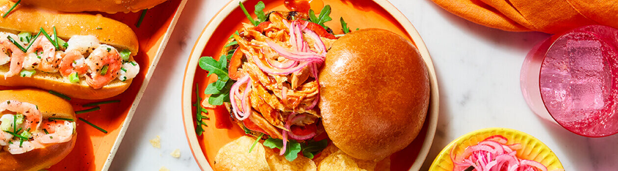 Orange round plate topped with a BBQ pulled Portuguese-style chicken sandwich.