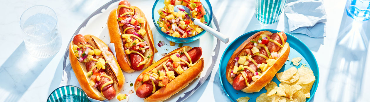 platter of Hawaiian-inspired hot dogs topped with bacon, salsa, mustard and chili powder