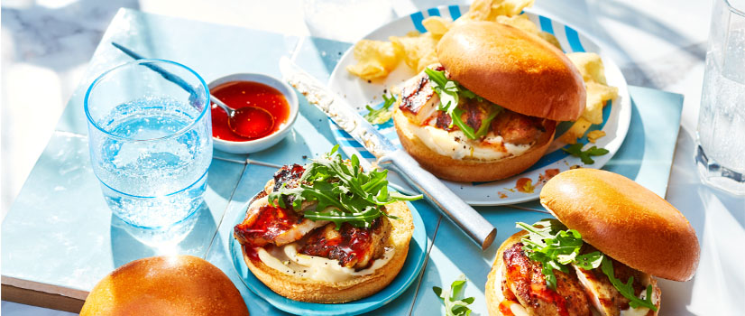 three Grilled Chicken Sandwiches with Harissa Hot Honey on a blue serving board