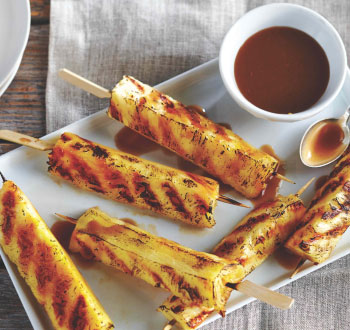 white platter of grilled pineapple skewers with caramel sauce