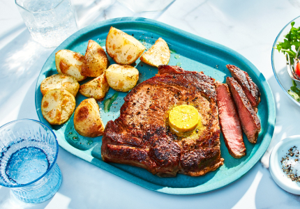 oval aqua dinner platter with grilled rib steak, potatoes and a side bowl of green salad