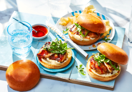 three sweet and spicy hot honey chicken sandwiches on blue wooden serving board