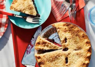 Red cutting board with pie, plates, lifter and one slice of pie served out on aqua plate