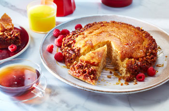Red plate with family-style grilled pancake topped with fresh raspberries and syrup