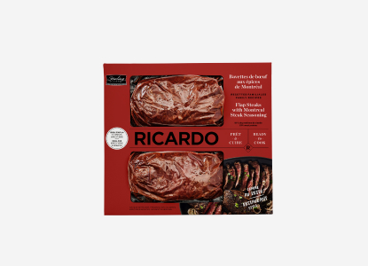 Red cardboard packaging with two portions of cryovac-wrapped Ricardo Flap Steaks with Montreal Steak Seasoning peering through the red package windows