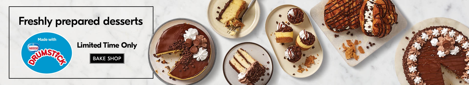 Selection of NESTLÃ‰ DRUMSTICK infused desserts ranging from a cake, cake slices and croissants on white plates, sitting on a neutral, marbled background.